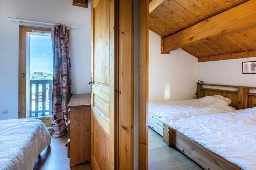 a bedroom with two beds and a large window at Résidence LES ALPAGES - Chalet CHALET ALPAGES 19 pour 10 Personnes 08 in Plagne Villages