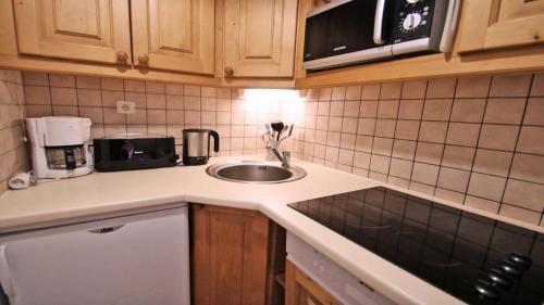 un comptoir de cuisine avec un évier et un micro-ondes dans l'établissement Résidence Dame Blanche - DBA304 - APPT 2 CHAMBRES + COIN MONTAGNE - BALCON - 8 PERSONNES MAE-3094, à Narreyroux
