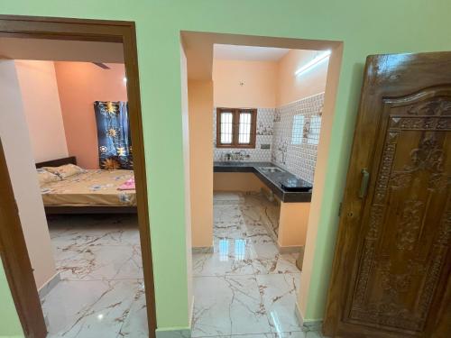a room with a bathroom with a bed and a door at Sai Ayush Homestay in Kumbakonam