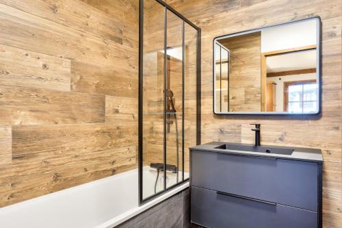 une salle de bain avec un lavabo, un miroir et une baignoire dans l'établissement Résidence Les Arcs 1950 Le Village - maeva Home - Appartement 3 pièces 6 personnes - Prestige MAE-5494, à Bourg-Saint-Maurice
