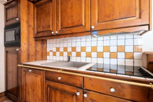 eine Küche mit Holzschränken und einem Waschbecken in der Unterkunft Résidence La Ginabelle - maeva Home - Appartement 3 pièces 6 personnes - P 904 in Chamonix-Mont-Blanc