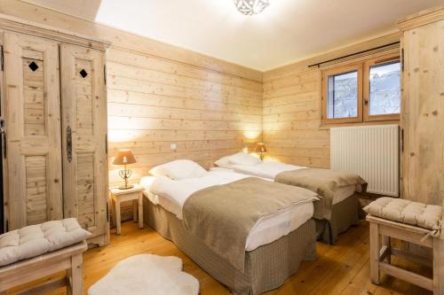 deux lits dans une chambre aux murs en bois dans l'établissement Résidence Les Fermes de Méribel - maeva Home - Appartement 3 pièces 6 personnes - Sélection MAE-7404, à Les Allues