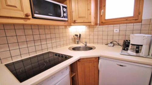 uma pequena cozinha com um lavatório e um micro-ondas em Résidence Dame Blanche - 2 Pièces pour 6 Personnes 034 em Narreyroux