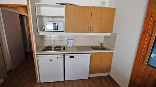 une petite cuisine avec un évier et un micro-ondes dans l'établissement Résidence Parc Aux Etoiles - A008PAE Appartement - 2 chambres avec terrasse - 4/6 PERS MAE-8644, à Narreyroux
