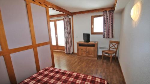 Cette chambre comprend un lit et un bureau avec une télévision. dans l'établissement Résidence Parc Aux Etoiles - A008PAE Appartement - 2 chambres avec terrasse - 4/6 PERS MAE-8644, à Narreyroux