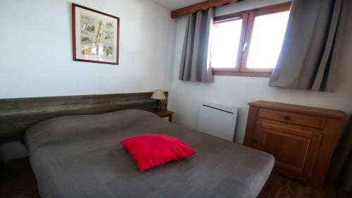 a bedroom with a bed with a red pillow on it at Résidence Dame Blanche - 2 Pièces pour 6 Personnes 074 in Narreyroux