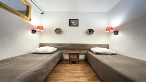 deux lits dans une pièce avec une table entre eux dans l'établissement Résidence Dame Blanche - DBA214 - APPT 1 CHAMBRE + CABINE - BALCON - 6 PERSONNES MAE-8074, à Narreyroux