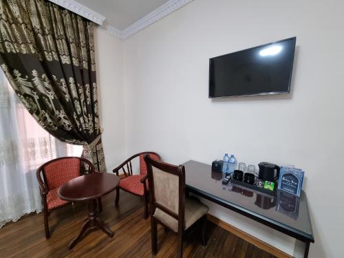 Habitación con mesa, sillas y TV. en Devon Begi Heritage Hotel, en Bukhara