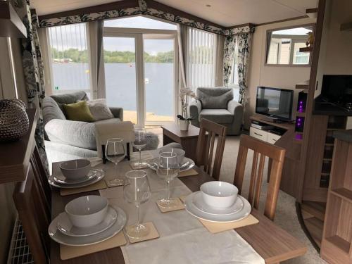 uma sala de estar com uma mesa com pratos e copos de vinho em Stunning LAKE SIDE Caravan with HOT TUB at Tattershall Lakes em Tattershall