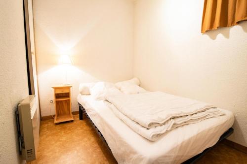 um pequeno quarto com uma cama e um candeeiro em Résidence Le Grand Vallon - Studio pour 4 Personnes 193135 em Villarodin-Bourget