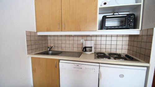une petite cuisine avec un évier et un micro-ondes dans l'établissement Résidence Parc Aux Etoiles - C104PAE - APPARTEMENT 2 CHAMBRES AVEC BALCON MAE-8824, à Narreyroux