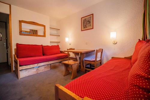 a room with two beds and a table with a red couch at PORTAIL G - Appartement PORTAIL 40 pour 2 Personnes 17 in Valmorel