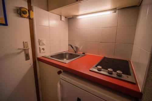 a small kitchen with a sink and a red counter top at PORTAIL G - Appartement PORTAIL 40 pour 2 Personnes 17 in Valmorel