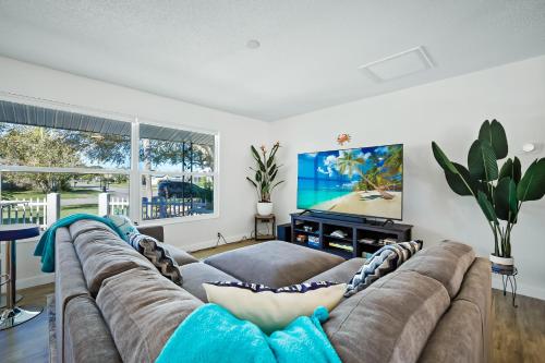 a living room with a couch and a flat screen tv at Ixora16 Heated Pool, mins to beach, airport, USSSA, Cruise Port, 1h to Disney in Melbourne