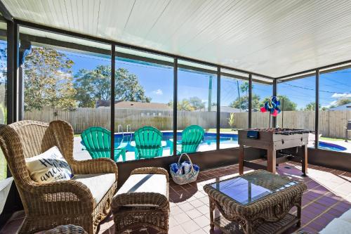 a screened in porch with chairs and a table at Ixora16 Heated Pool, mins to beach, airport, USSSA, Cruise Port, 1h to Disney in Melbourne