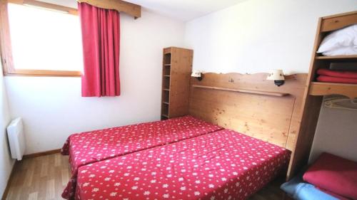 1 dormitorio pequeño con 1 cama con colcha roja en Résidence Hameau Des Ecrins - Appartements pour 6 Personnes 874, en Narreyroux