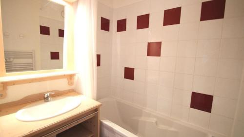 uma casa de banho com um lavatório, uma banheira e um espelho. em Résidence Les Gentianes - Appartements pour 6 Personnes 984 em Narreyroux