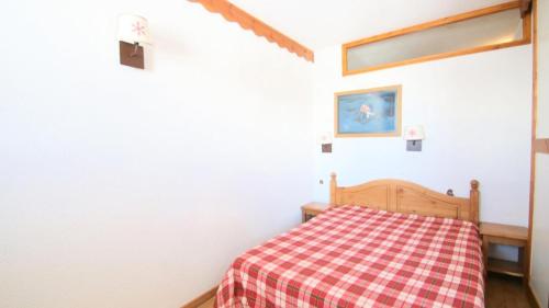 una camera da letto con un letto con una coperta a quadri di Résidence Parc Aux Etoiles - C313PAE - APPARTEMENT 2 CHAMBRES AVEC BALCON MAE-9054 a Narreyroux