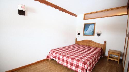 Schlafzimmer mit einem Bett mit einer roten und weißen karierten Decke in der Unterkunft Résidence Parc Aux Etoiles - Appartements pour 6 Personnes 064 in Narreyroux