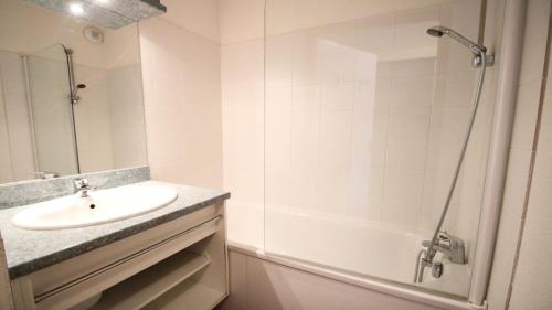 ein weißes Bad mit einem Waschbecken und einer Dusche in der Unterkunft Résidence Parc Aux Etoiles - Appartements pour 6 Personnes 064 in Narreyroux