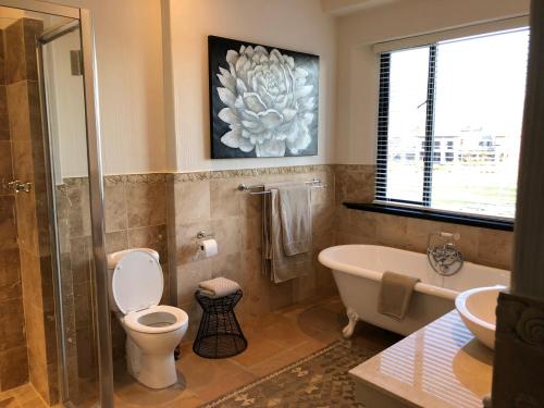 a bathroom with a toilet and a tub and a sink at Santé Wellness Retreat & Spa in Paarl