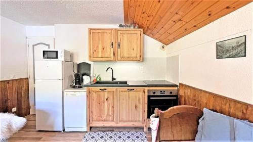 une cuisine avec des armoires en bois et un réfrigérateur blanc dans l'établissement Le Chalet - CHALEUREUX APPARTEMENT AU PIED DES PISTES - 4/6 PERS MAE-9104, à Puy-Saint-Vincent