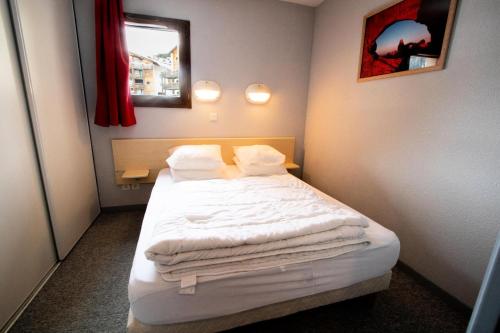 ein kleines Schlafzimmer mit einem Bett mit weißer Bettwäsche und Kissen in der Unterkunft Résidence Les Balcons De La Vanoise - 2 Pièces pour 6 Personnes 193186 in Villarodin-Bourget