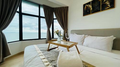 a bedroom with a bed with a table and windows at Mutiara Melaka Beach Resort by Glex in Tangga Batu
