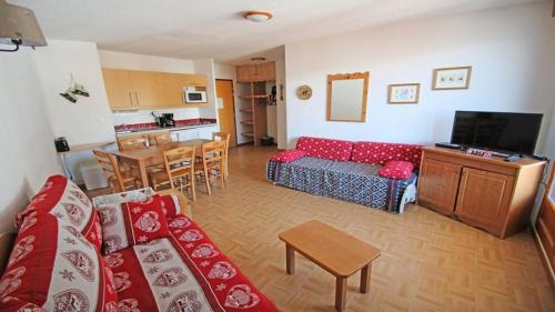 un salon avec un canapé rouge et une cuisine dans l'établissement Résidence Parc Aux Etoiles - GEC35 - APPARTEMENT 2 CHAMBRES AVEC BALCON VUE VALLÉE MAE-8894, à Narreyroux