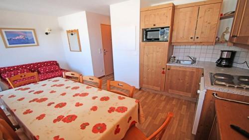 une cuisine avec une table et une cuisine avec une table et des chaises dans l'établissement Résidence Hameau Des Ecrins - HEC112 - APPARTEMENT 6 PERSONNES, SECTEUR 1700M MAE-8994, à Narreyroux