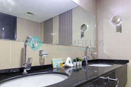 uma casa de banho com 2 lavatórios e um espelho grande em Relaxing 2 Bedrooms In Rak em Abu Dhabi