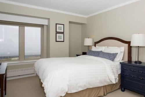 um quarto com uma grande cama branca e uma janela em Spacious Waterfront Apt #801 with AC em Halifax