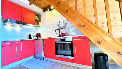 une cuisine avec des placards rouges et un escalier dans l'établissement Résidence Valérianes - Appartements pour 6 Personnes 124, à Vallouise