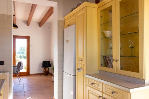 a kitchen with yellow cabinets and a refrigerator at Natursteinfinca mit Meerblick & Pool in Porto Cristo