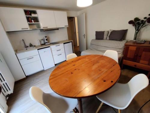 - une cuisine avec une table en bois et des chaises blanches dans l'établissement Le Chalet - CHALEUREUX APPARTEMENT AU PIED DES PISTES -6 PERS MAE-9174, à Puy-Saint-Vincent