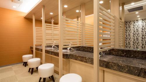 a bathroom with a sink and white stools at APA Hotel Okayama Ekimae in Okayama