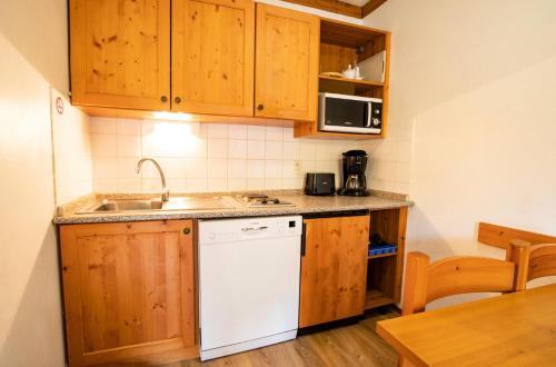 - une cuisine avec des placards en bois et un lave-vaisselle blanc dans l'établissement Chalets Du Thabor - CHALETS DU THABOR - CTHAA9 MAE-3196, à Modane