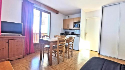 un soggiorno con tavolo, sedie e TV di Résidence Les Gentianes - Appartements pour 6 Personnes 204 a Narreyroux