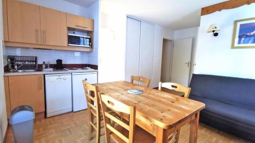 a kitchen and dining room with a wooden table and chairs at Résidence Les Gentianes - Appartements pour 6 Personnes 204 in Narreyroux
