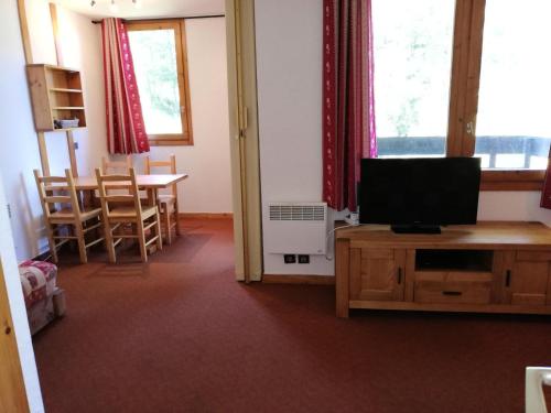 Zimmer mit einem Tisch, einem TV und einem Esszimmer in der Unterkunft CACHETTE G - Appartement CACHETTE 24 pour 4 Personnes 40 in Valmorel