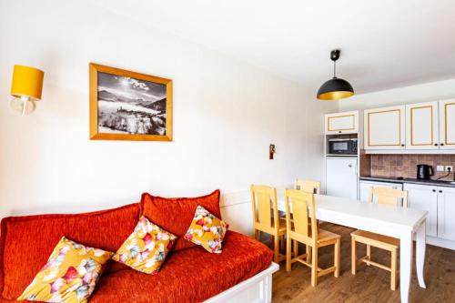 un salon avec un canapé rouge et une cuisine dans l'établissement Résidence Le Thabor - maeva Home - Appartement 3 pièces 6 personnes - Sélection MAE-4944, à Le Désert