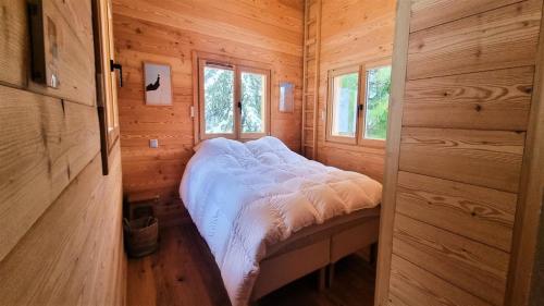 a small bedroom with a bed in a wooden cabin at Chalet Piganiol-puy-saint-vincent - Chalets 684 in Les Prés