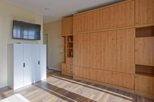um quarto com armários de madeira e uma televisão na parede em Haus Atlantic, FeWo 513 em Döse