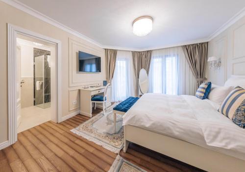 a bedroom with a bed and a desk and a bathroom at Grant Boutique Hotel in Arad