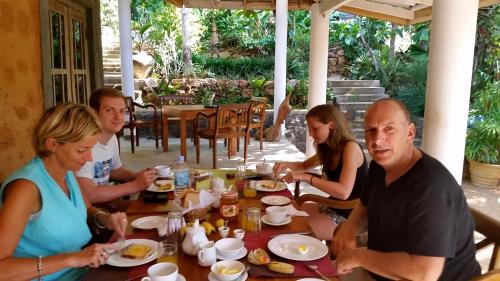 a group of people sitting around a table eating food at Landa Holiday House in Belihul Oya