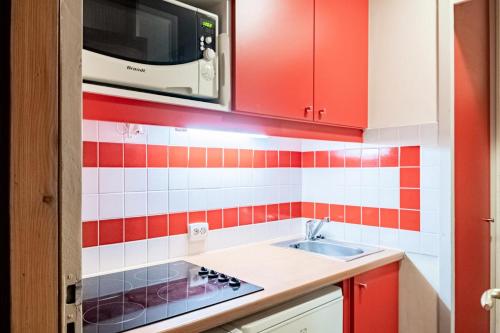 - une cuisine avec du carrelage rouge et blanc sur le mur dans l'établissement Résidence Plagne Lauze - maeva Home - Studio 4 personnes - Sélection MAE-3734, à Mâcot La Plagne