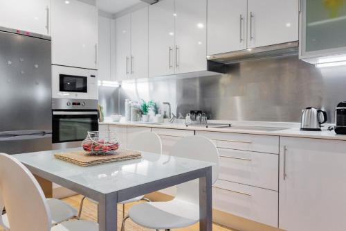 a kitchen with white cabinets and a table and chairs at Calle Suevia 13 in A Coruña