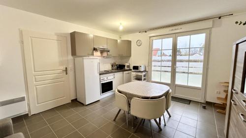 une cuisine avec une table et un réfrigérateur blanc dans l'établissement Les Courlis, à Saint-Valery-sur-Somme