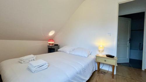 une chambre avec un lit blanc avec des serviettes dessus dans l'établissement Les Courlis, à Saint-Valery-sur-Somme