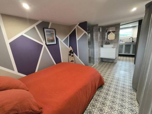 - une chambre avec un lit orange et une salle de bains dans l'établissement Studio calme et proche de Rennes, à Vezin-le-Coquet